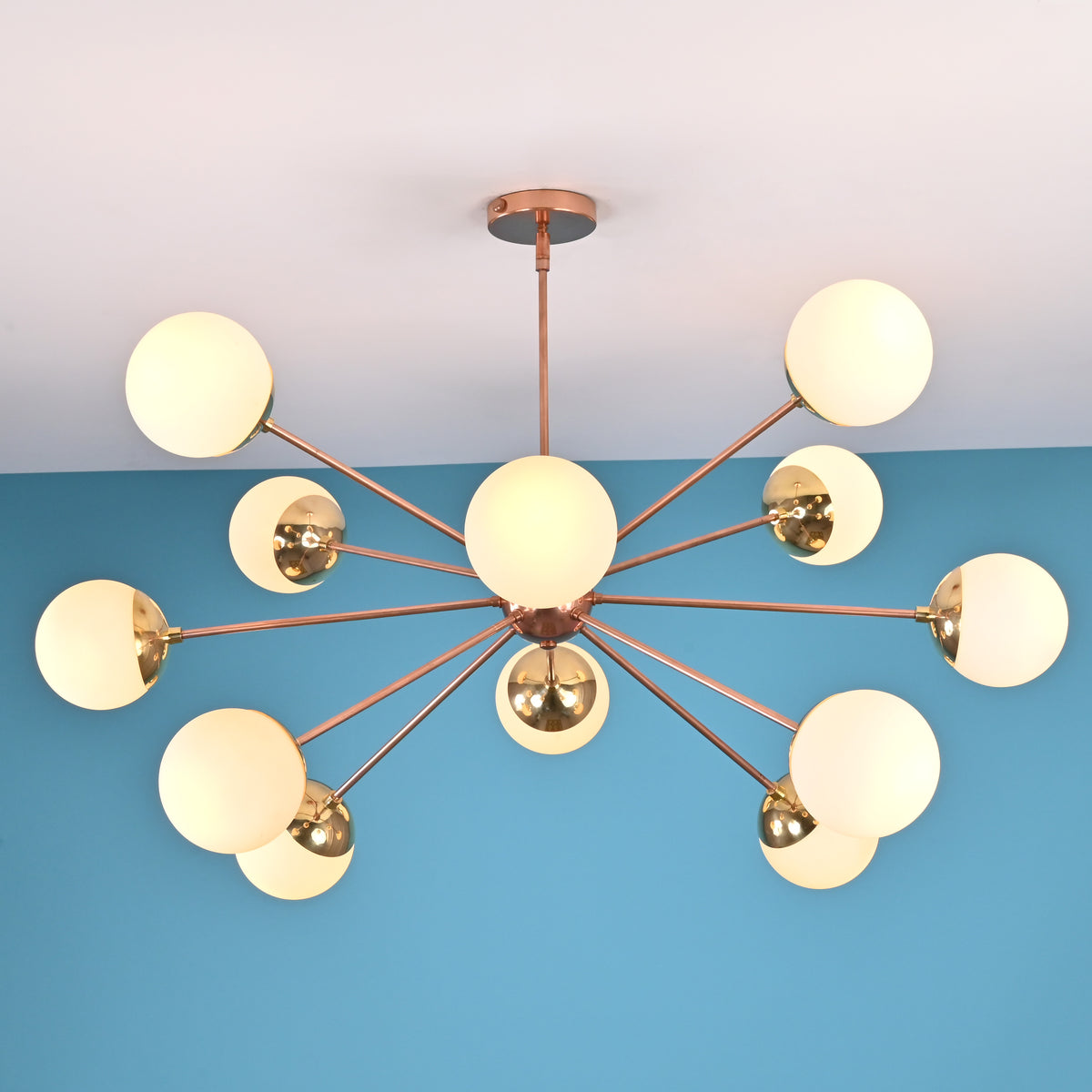 Illuminated 12 opal glass sputnik chandelier in brushed brass finish creating warm ambient light