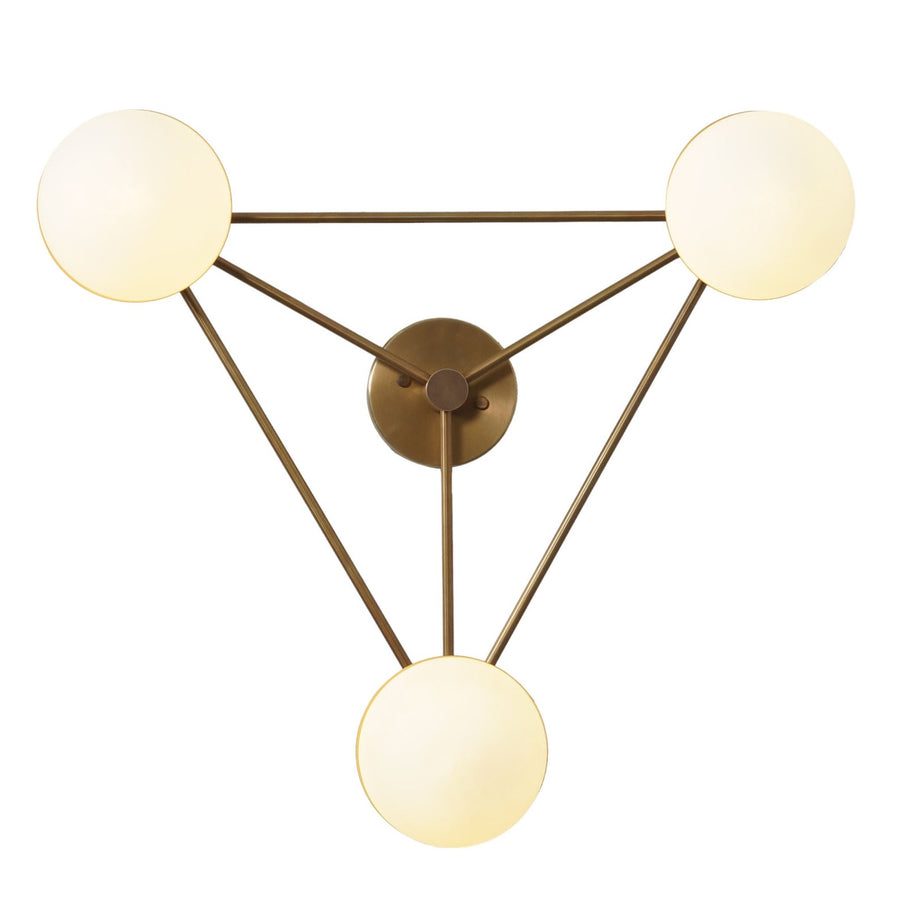 Angled view of brass geometric chandelier with three frosted globes forming a triangle, highlighting mid-century modern craftsmanship and warm illumination.