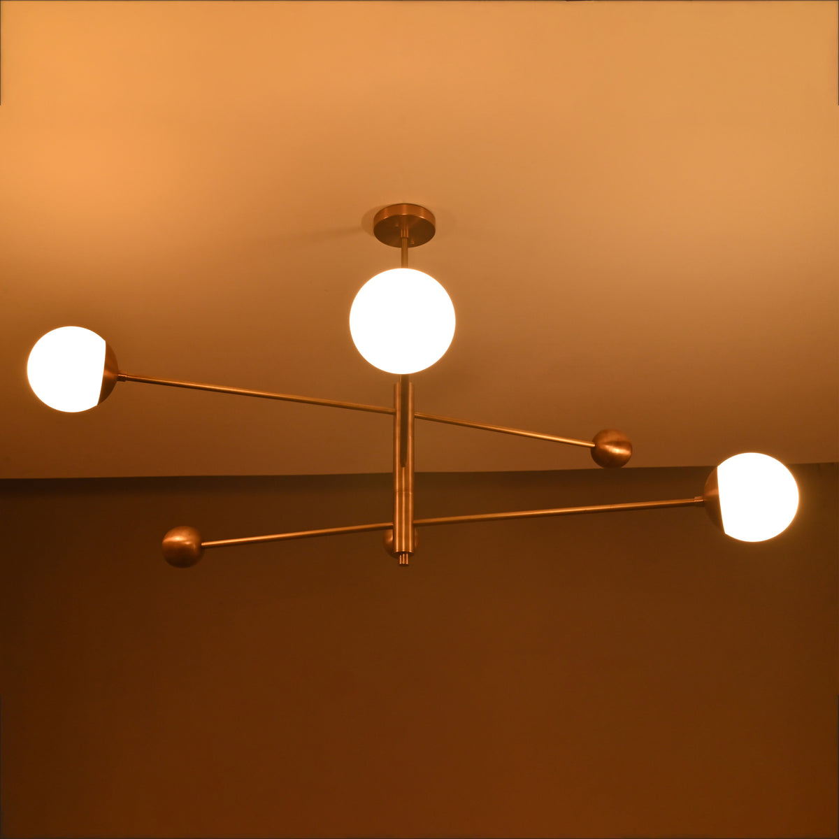 3-globe brass chandelier illuminated at night, showing warm ambient glow from frosted glass globes.