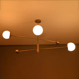 3-globe brass chandelier illuminated at night, showing warm ambient glow from frosted glass globes.