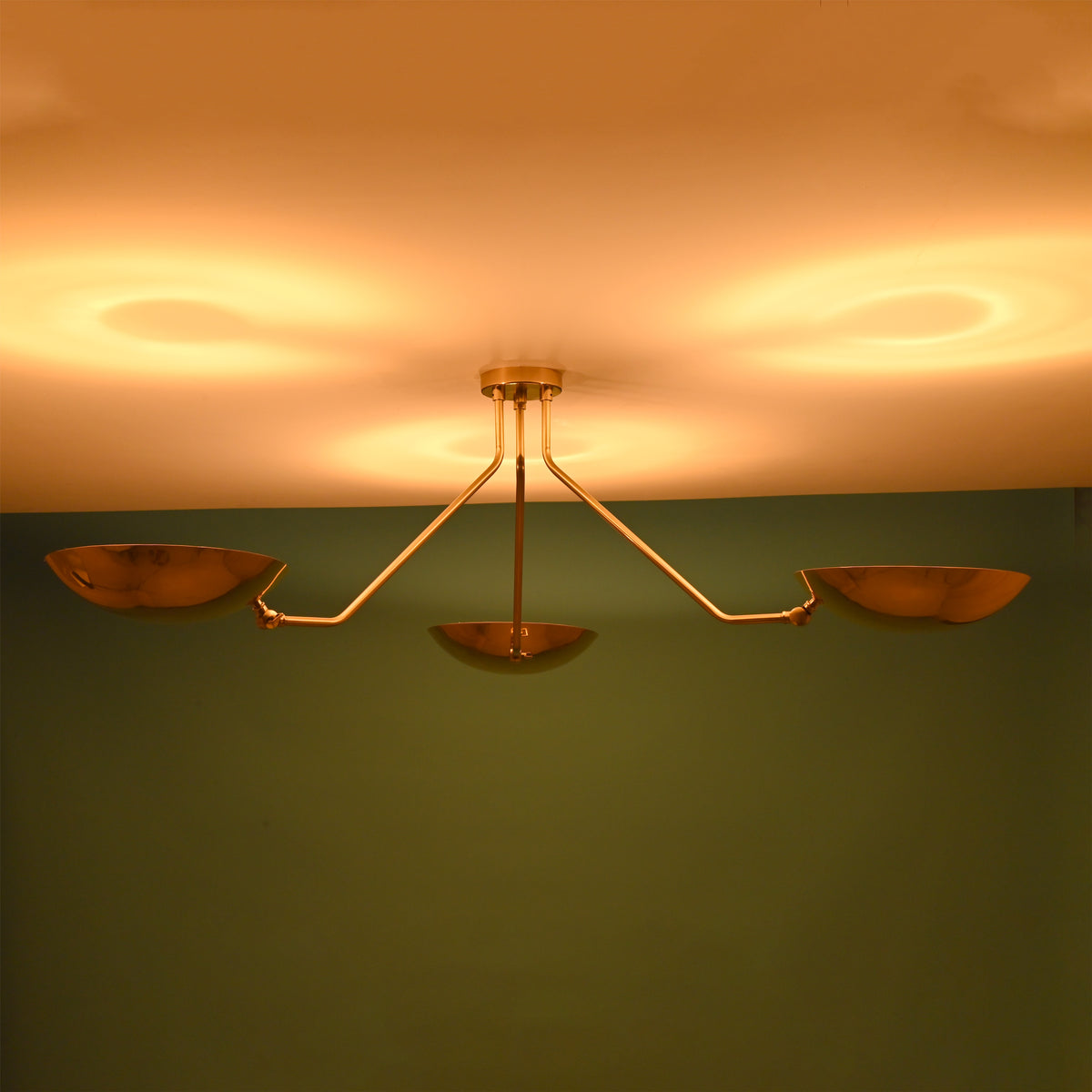 3 light brass bowl ceiling light emitting warm indirect ambient glow against modern interior wall