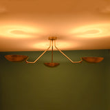 3 light brass bowl ceiling light emitting warm indirect ambient glow against modern interior wall