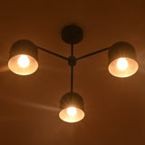 Bottom view of a 3 light brass chandelier highlighting bowl shades and warm downward lighting.