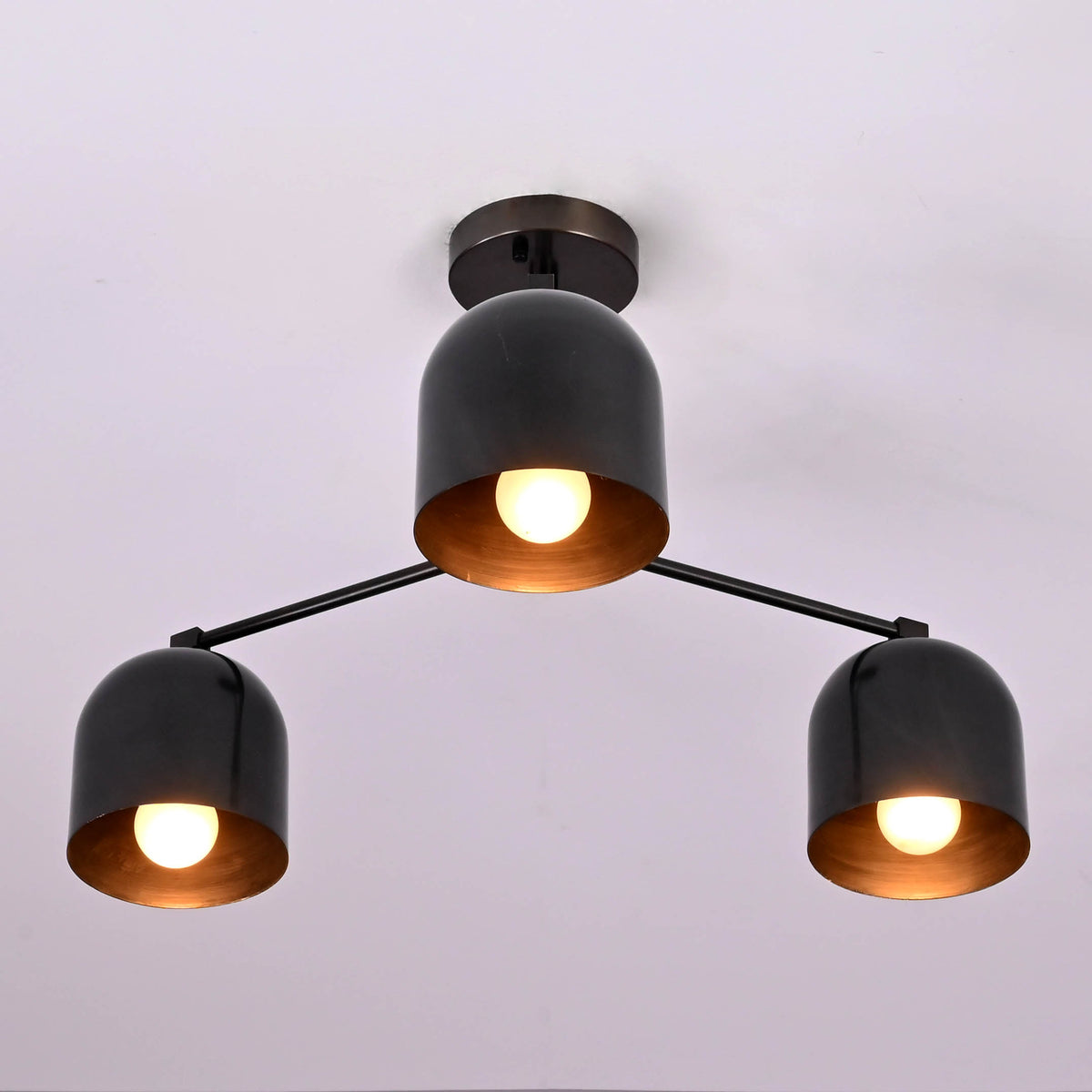Angled view of a modern industrial 3 light brass chandelier with bowl-shaped shades.