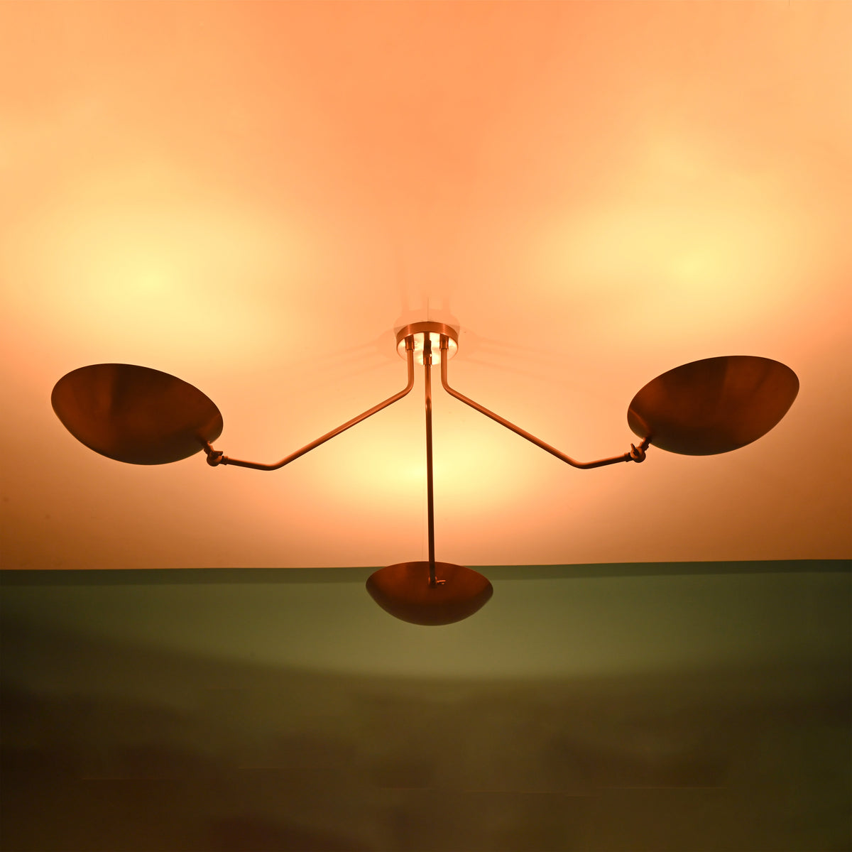 Three light brass ceiling fixture providing soft indirect uplighting with warm glow for contemporary interiors