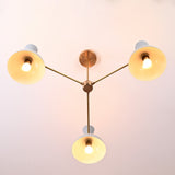 Bottom view of 3-light brass chandelier with white bowl-shaped shades and modern minimalist arms.