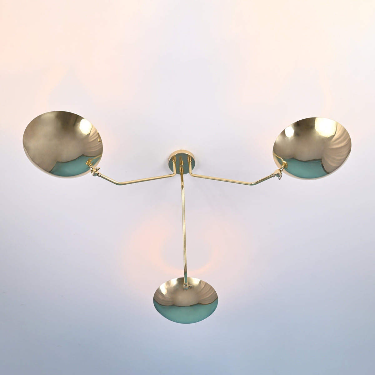 Bottom view of 3 light brass disc ceiling light with bowl shaped shades and clean symmetrical arms