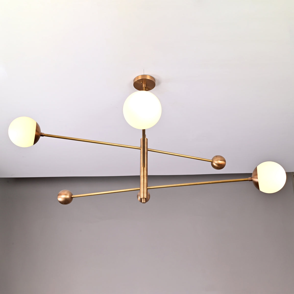 Minimalist brass chandelier with three opal glass globes, elegant ceiling light with customizable dimensions.