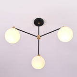 Angled perspective of a modern brass chandelier featuring three glowing opal glass globes.