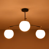 Opal glass globe brass chandelier creating a warm, ambient ceiling glow in a modern space.