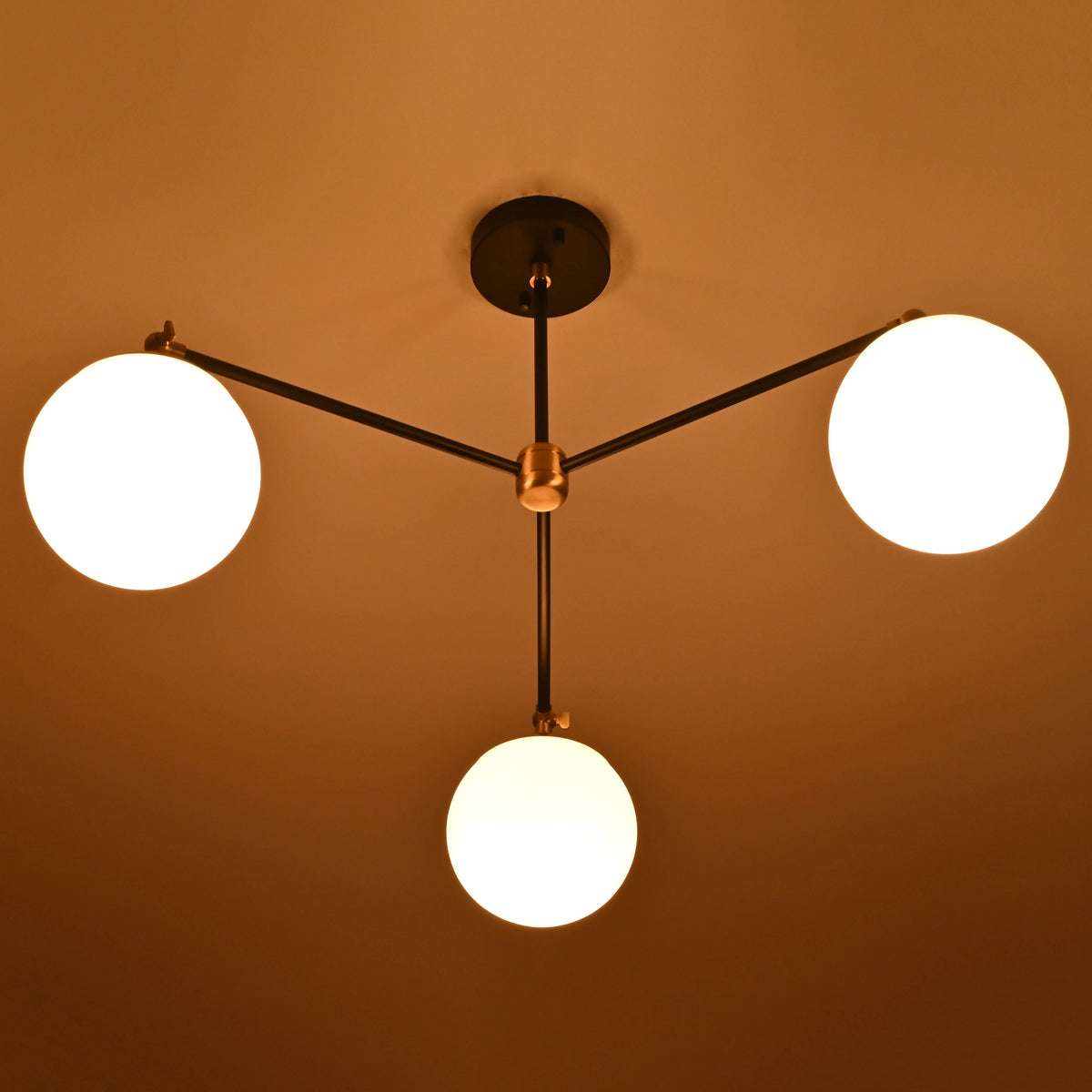 Evening view of a brass chandelier with opal glass globes casting soft, warm light.