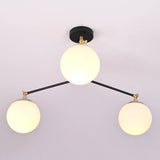 Symmetrical layout of a handcrafted 3 light opal glass globe chandelier with minimalist brass detailing.
