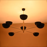 Modern Industrial Brass Chandelier with Black Shades – Glowing Ceiling Light in Warm Tone