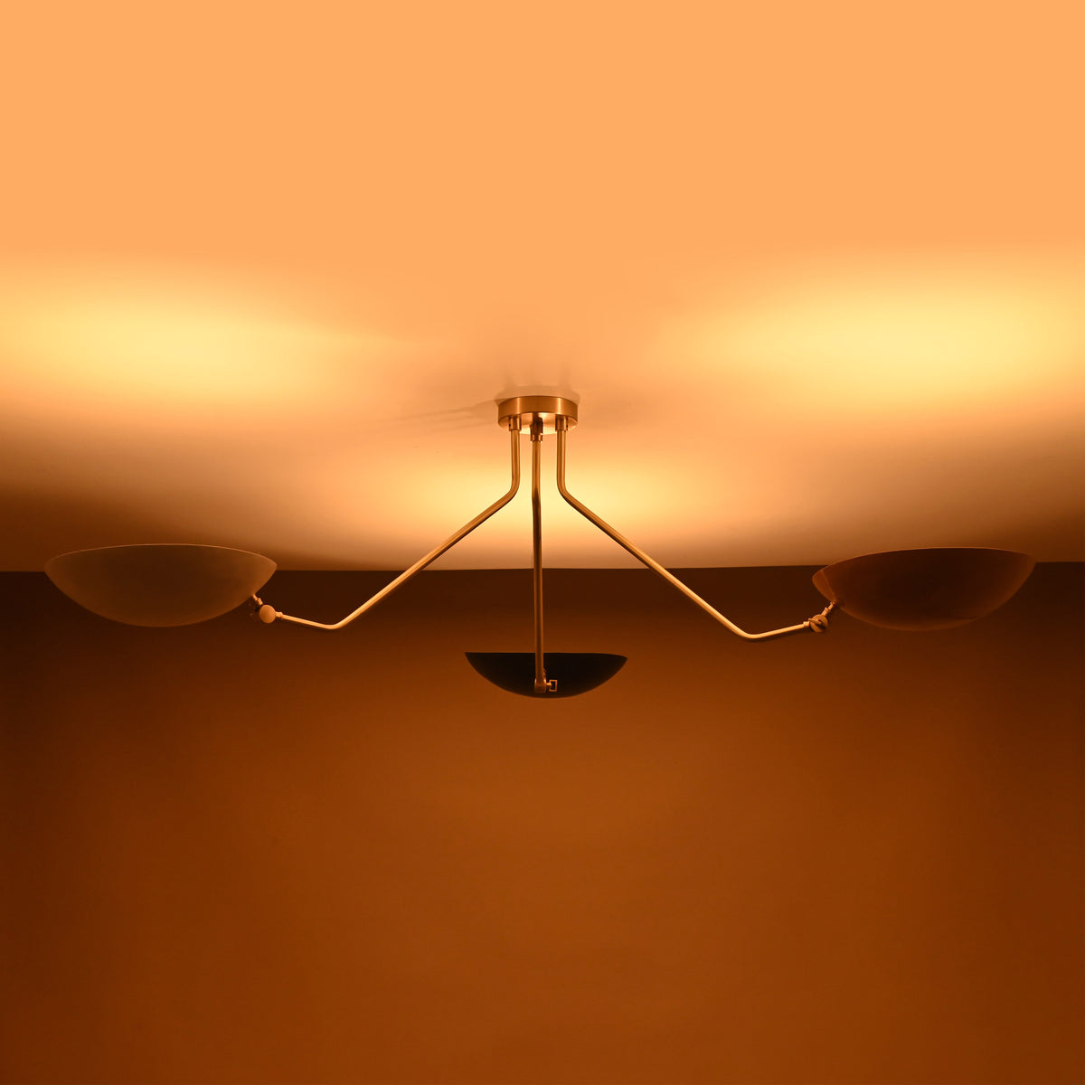 Ambient lighting view of brass 3-light ceiling fixture with bowl-shaped reflectors