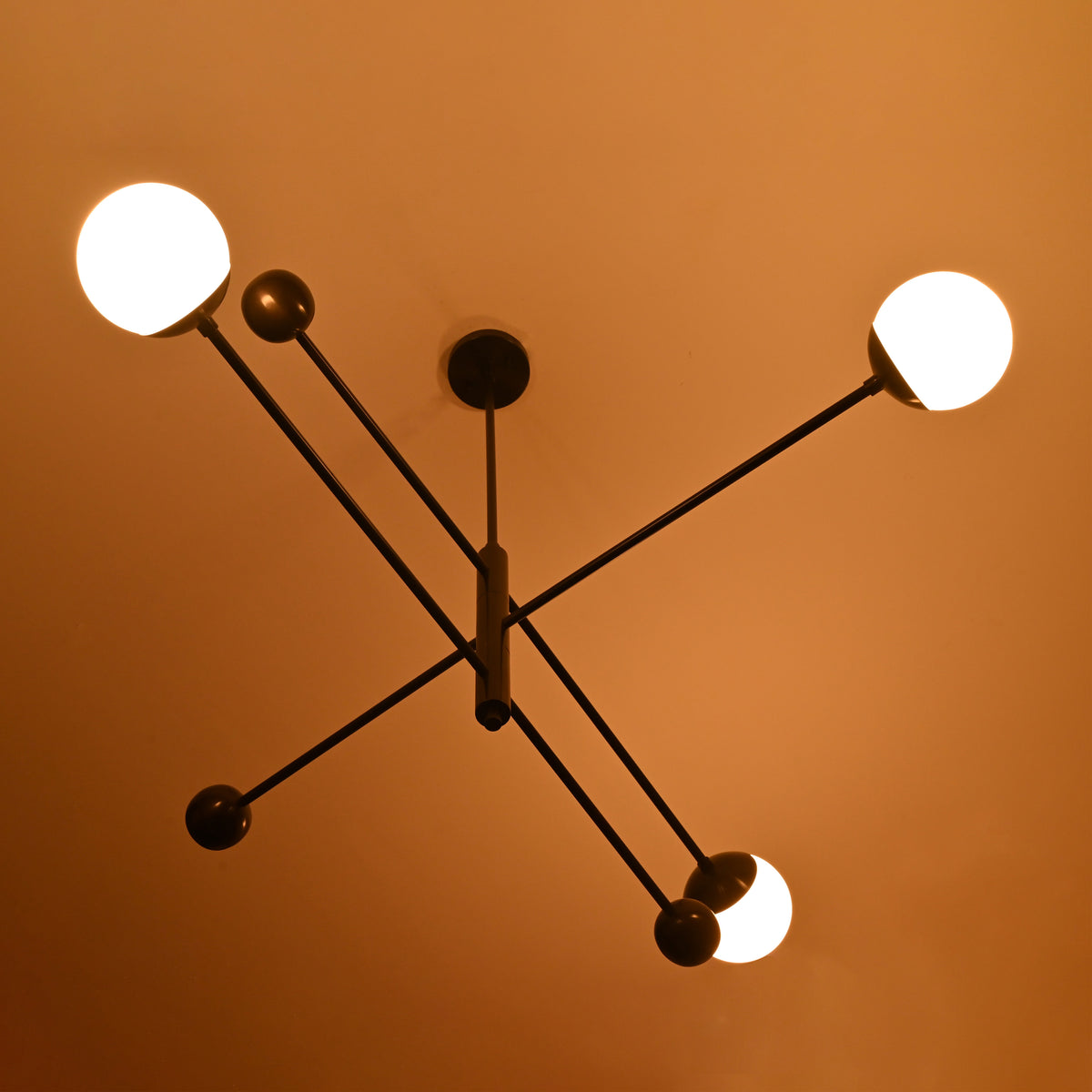 3-light modern black brass chandelier illuminated with warm lighting – ceiling view