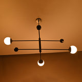 Matte black balance chandelier softly glowing in warm ambient light – diagonal angle