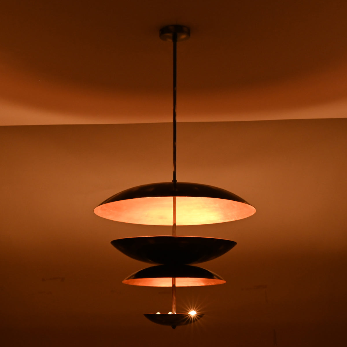 Tall three-tier pendant chandelier with black exterior and copper inner finish