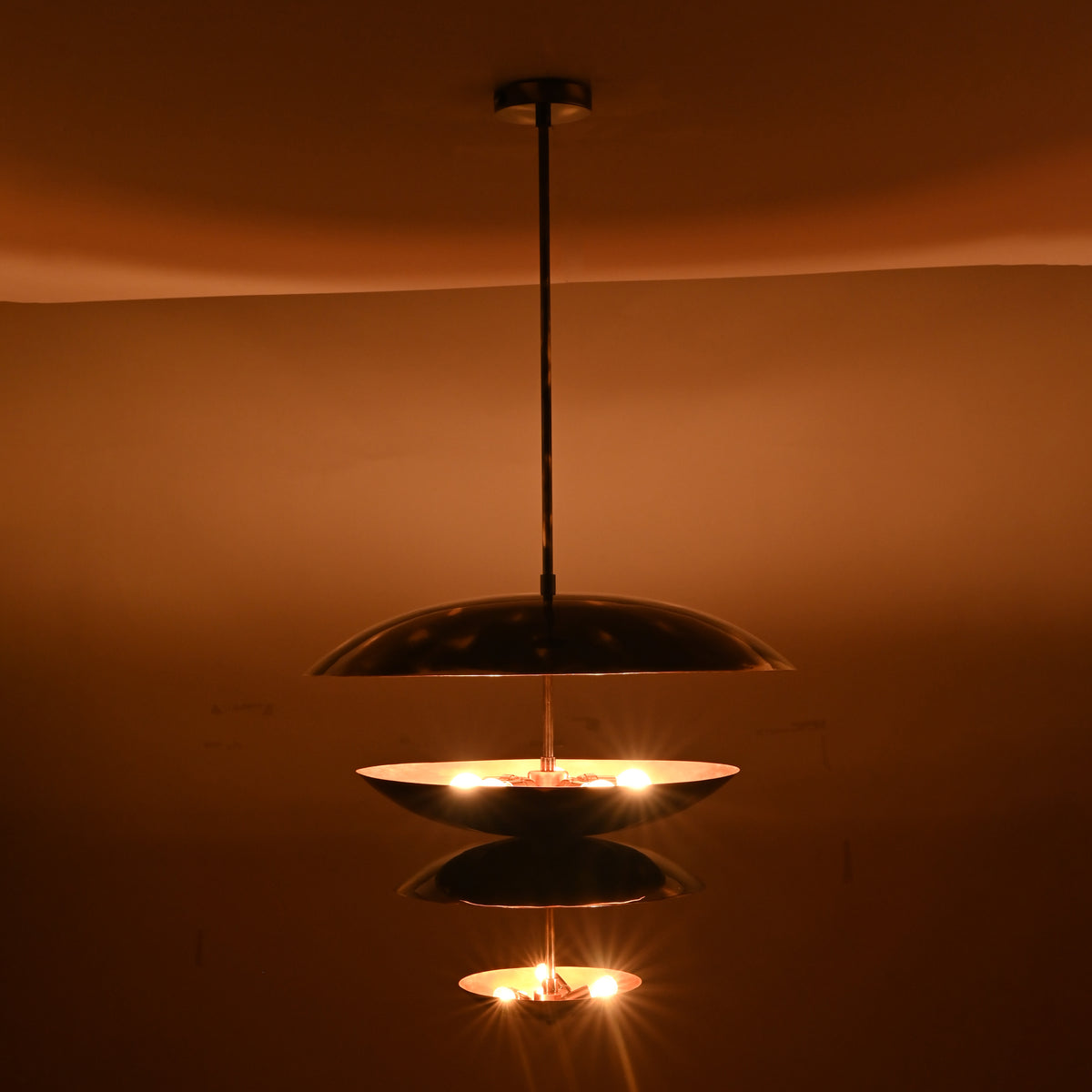 Modern sculptural brass bowl chandelier illuminated at night