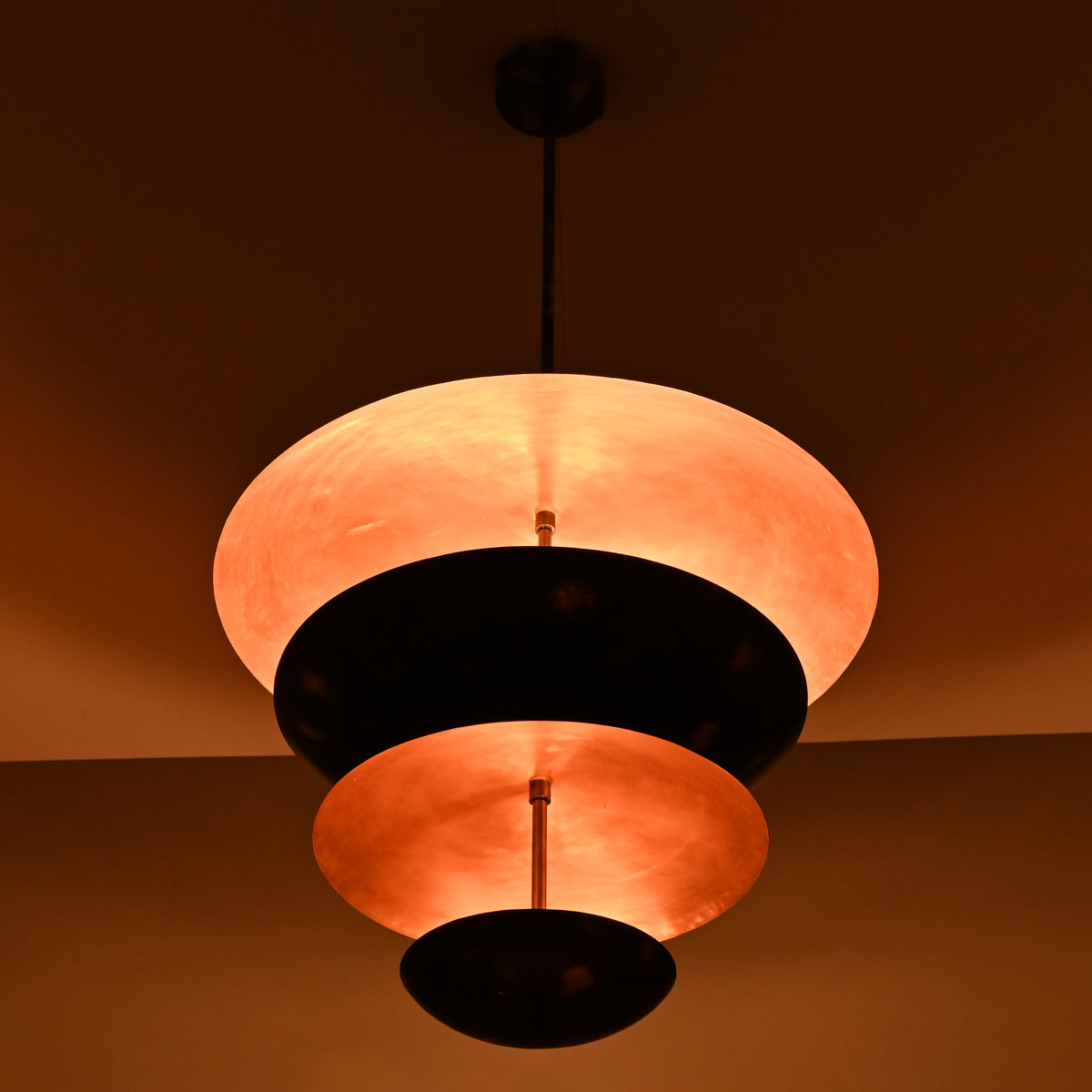 Side view of modern tiered brass chandelier with warm ambient lighting