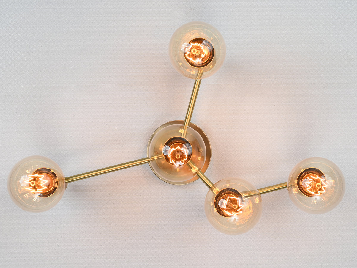 Sculptural five-light brass wall sconce with exposed bulbs