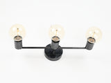 Modern brass vanity wall light with three exposed bulbs