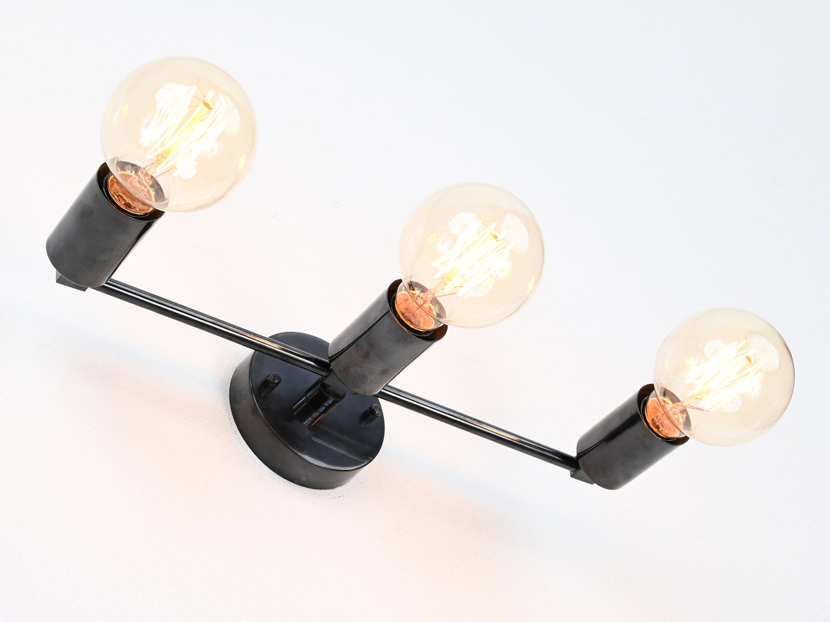 Linear three-light brass wall sconce with exposed bulbs