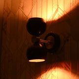 Brass Leaf Studio burgundy double globe wall sconce lit, creating striking light patterns on geometric wall design.