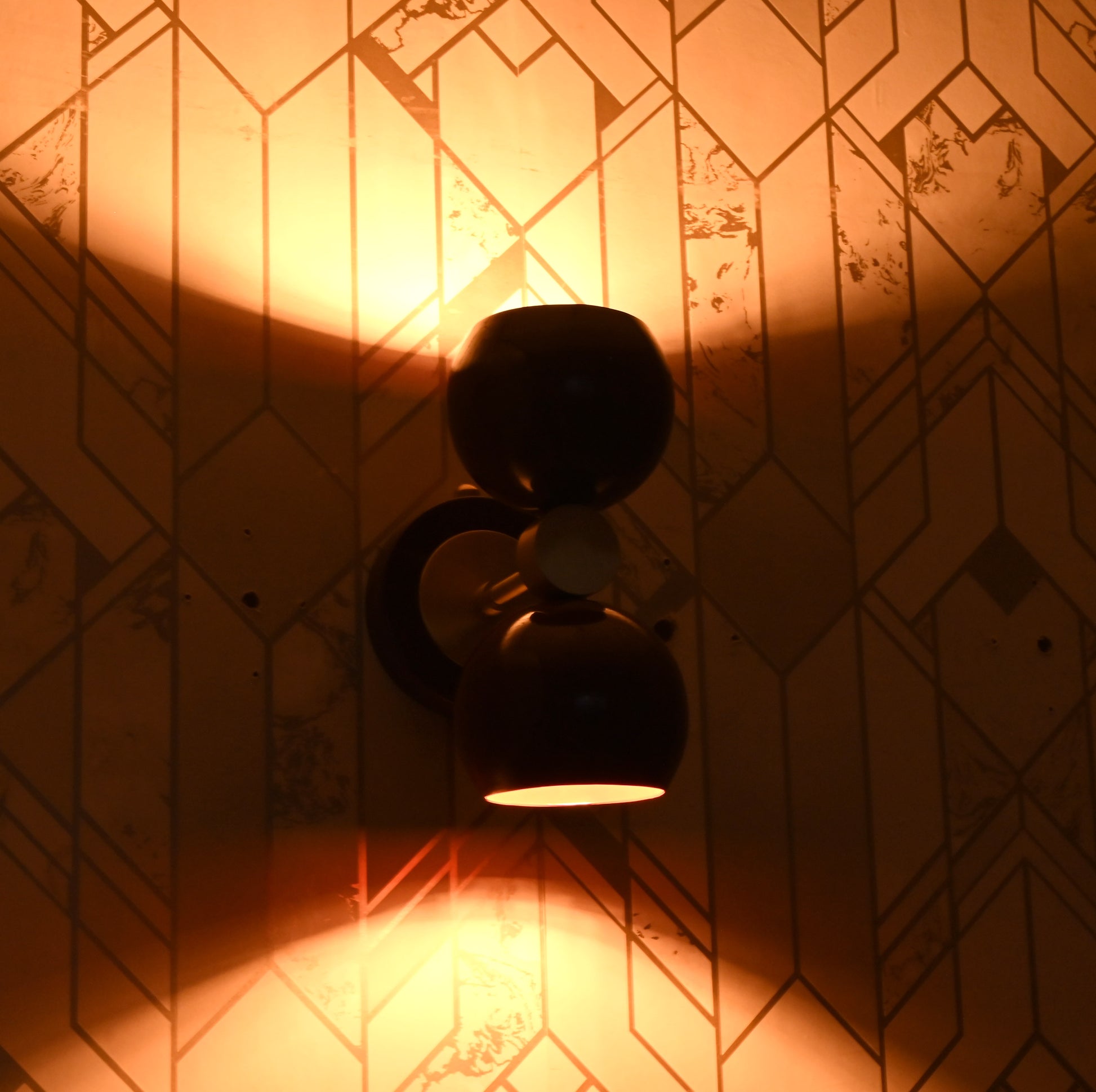 Side angle night shot of burgundy double globe wall sconce, glowing warmly with both up and down lighting.