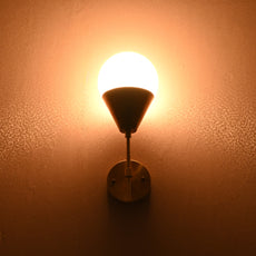 Globe-shaped brass wall sconce glowing warmly against wall, creating ambient lighting.