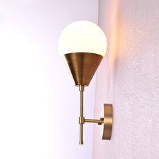 Side view of brass wall sconce with frosted globe shade and brushed brass finish.