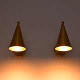 Two matching cone-shaped wall sconces in a warm brass or bronze finish, mounted side by side on a wall and casting a soft warm glow downward.