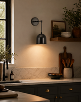 Harlow modern black dome wall sconce installed in a contemporary kitchen creating warm task and ambient lighting.