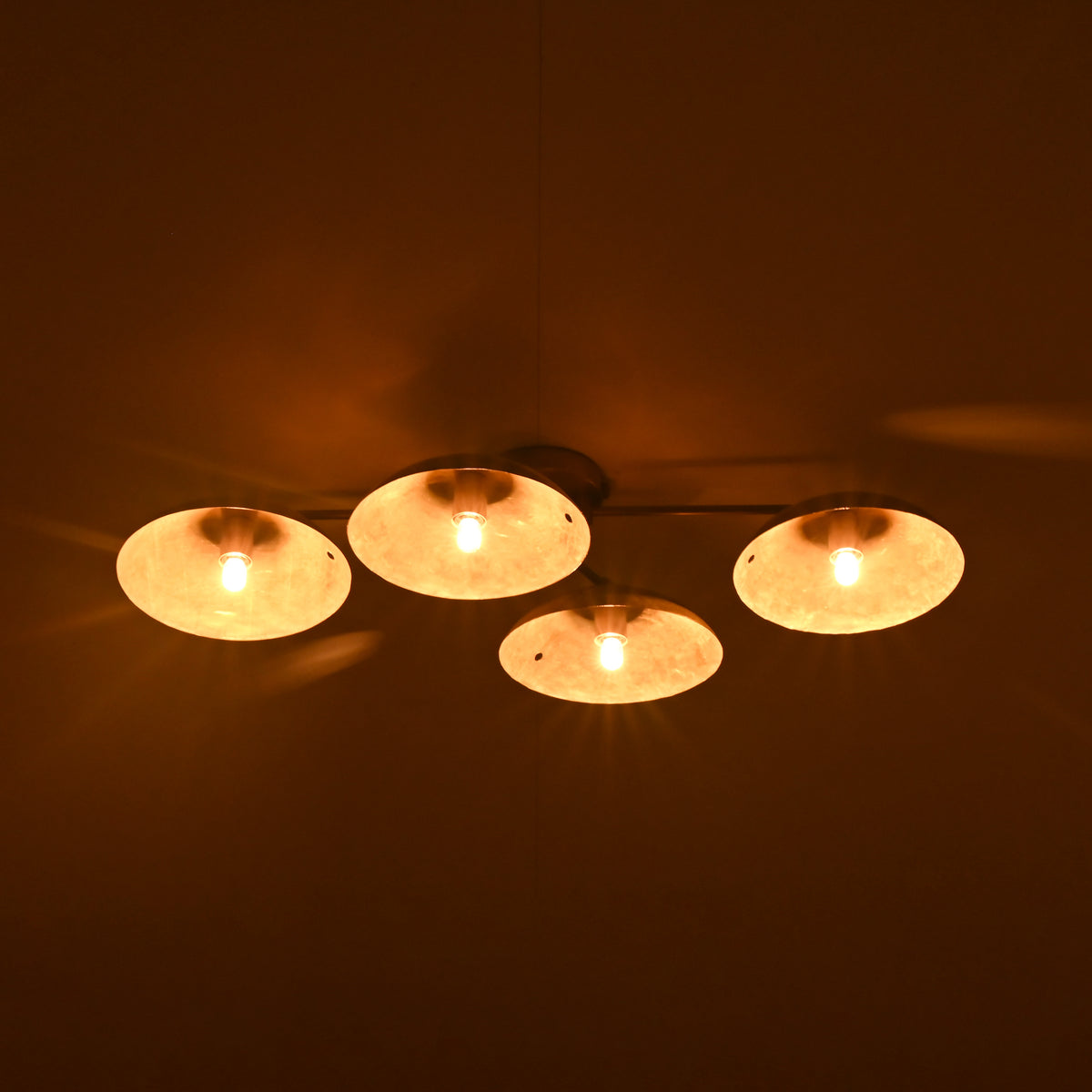 Ceiling light fixture with four round lights on a dark background