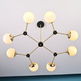 Top-down view of an eight-globe brass chandelier with black connector accents, mounted on a white ceiling.