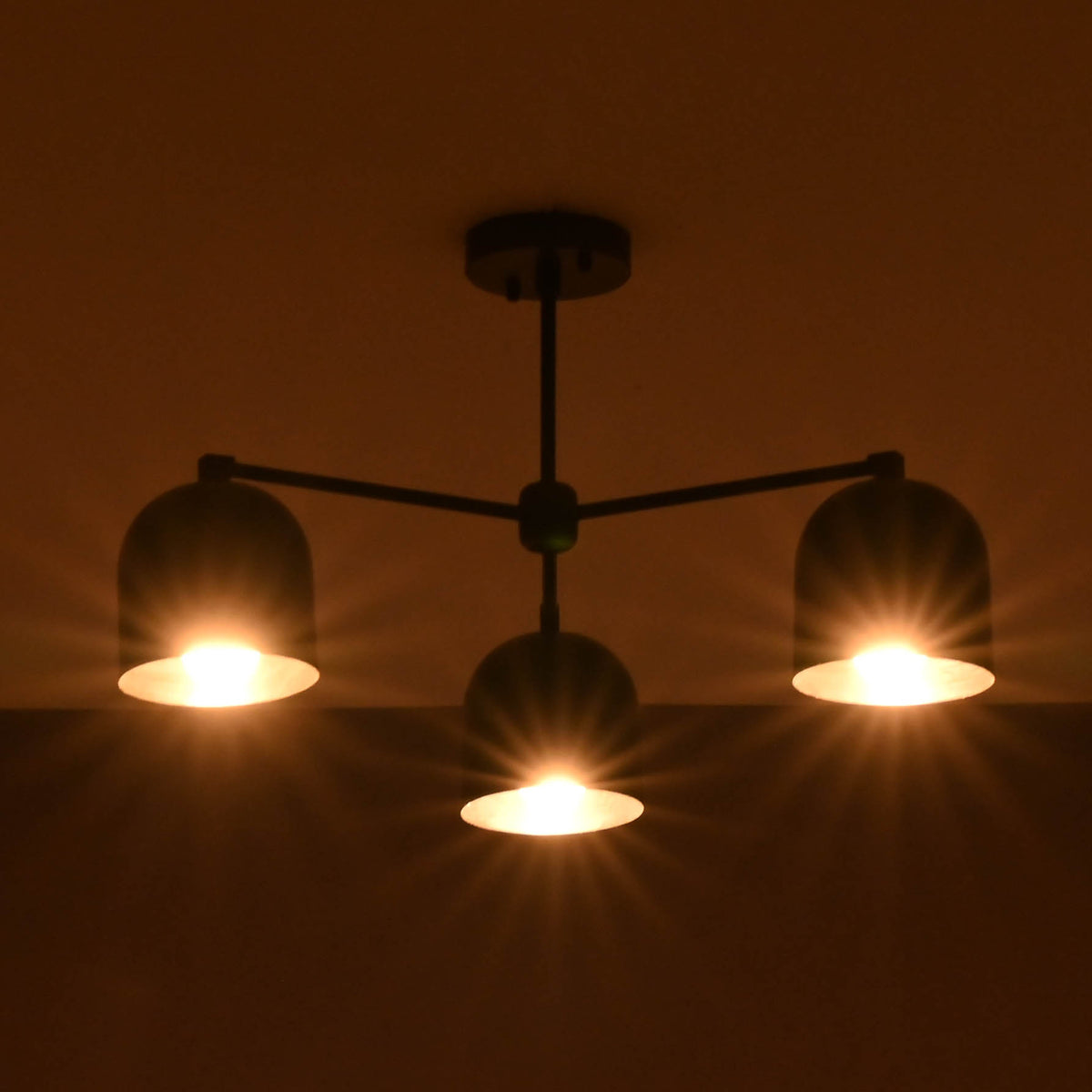 Modern chandelier with three illuminated lights against a dark background
