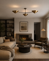 A modern living room featuring a beige sectional sofa, a dark round coffee table, a brown armchair, a built-in fireplace, and a three-light brass ceiling fixture.