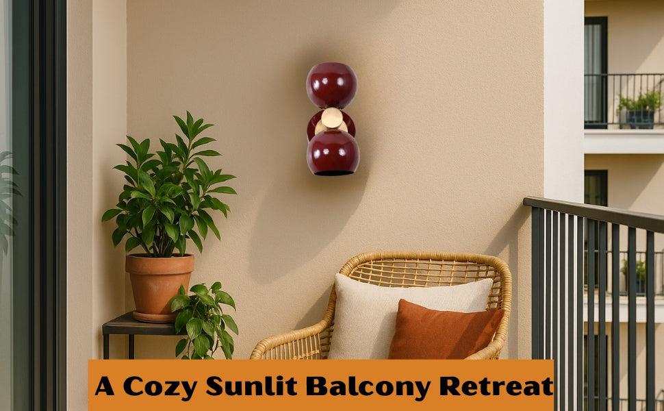 Brass Leaf Studio burgundy double globe wall light illuminating a cozy balcony corner with plants and wicker chair.