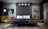 Contemporary brass chandelier with eight white globe lights hanging in a modern dark-themed bedroom with blue bed covers.