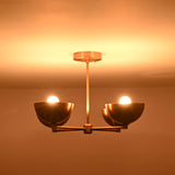 Side profile of a 4 bowl brass chandelier in low light, showcasing the balanced arm structure and warm reflective brass surface.