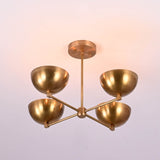 4 bowl brass chandelier illuminated to show warm ambient indirect lighting that softly reflects off the brushed brass finish.