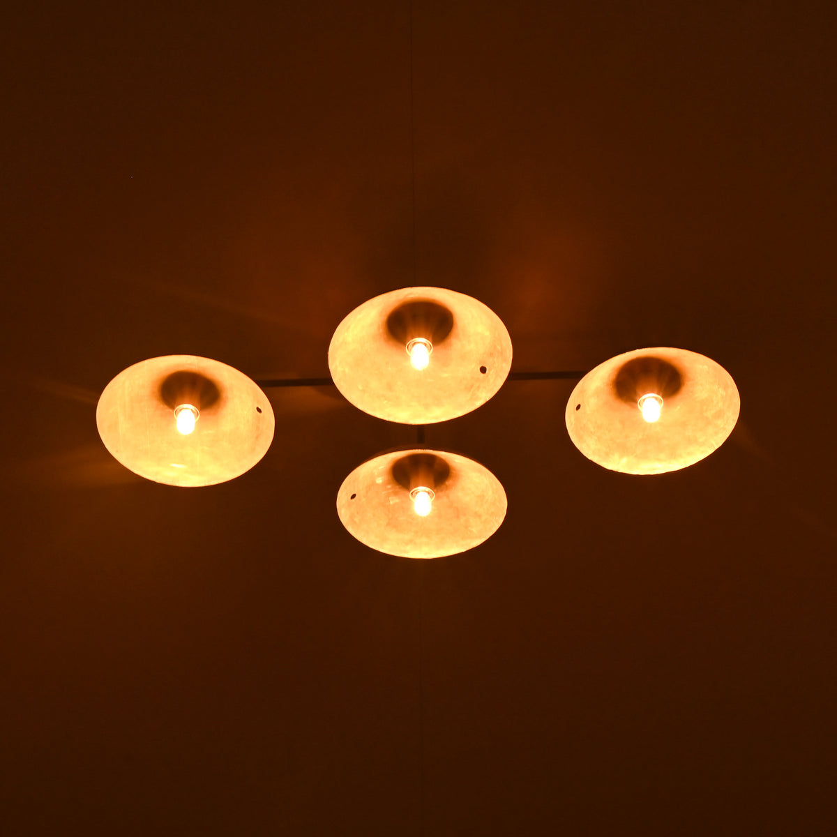 View of a 4-light brass flush mount fixture in low-light ambiance, showcasing soft indirect lighting on the ceiling.