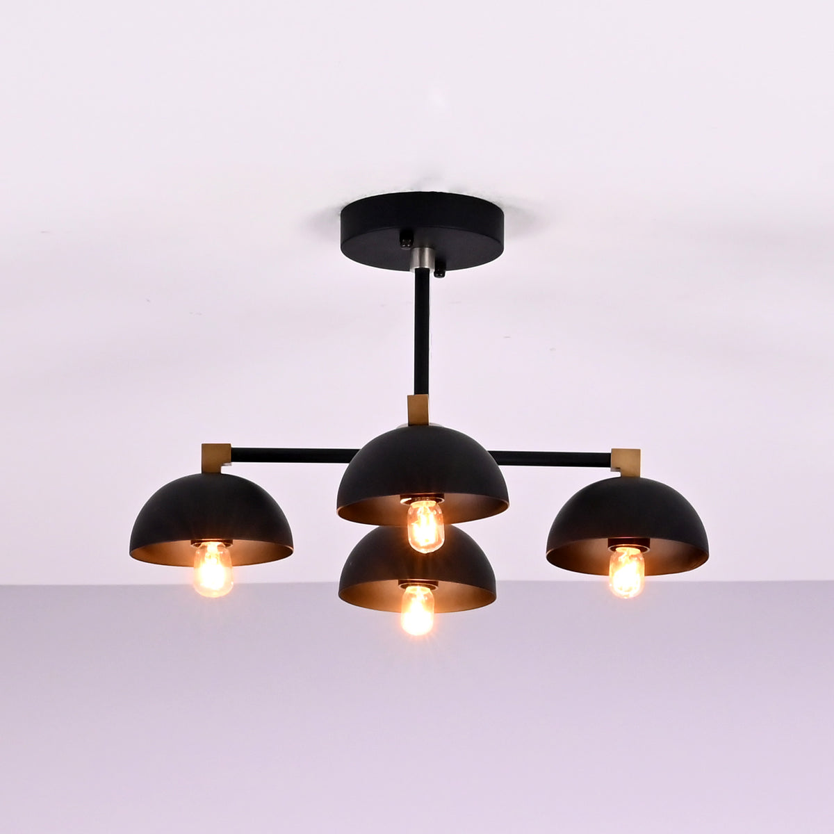 Side view of modern 4 light flush mount chandelier with black dome shades and brass accents