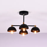 Side view of modern 4 light flush mount chandelier with black dome shades and brass accents
