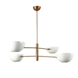 Side view of 4-light brass chandelier featuring minimalist white dome shades for soft illumination