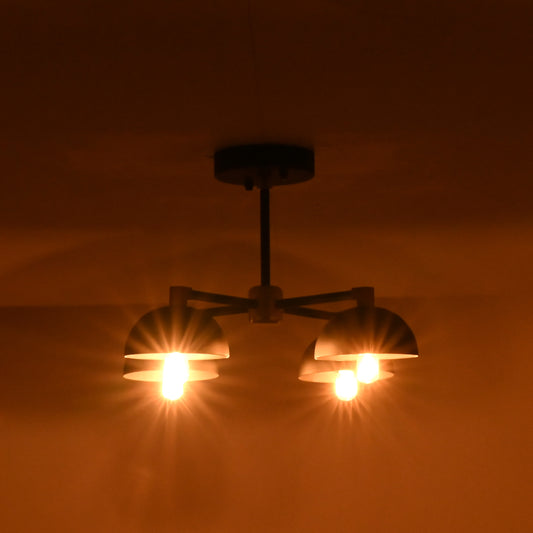 Industrial style 4 light brass and black flush mount ceiling lamp glowing warmly in a dark room