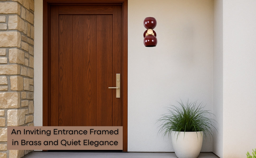 Brass Leaf Studio double globe wall sconce mounted beside a modern wooden front door, styled with a potted plant.