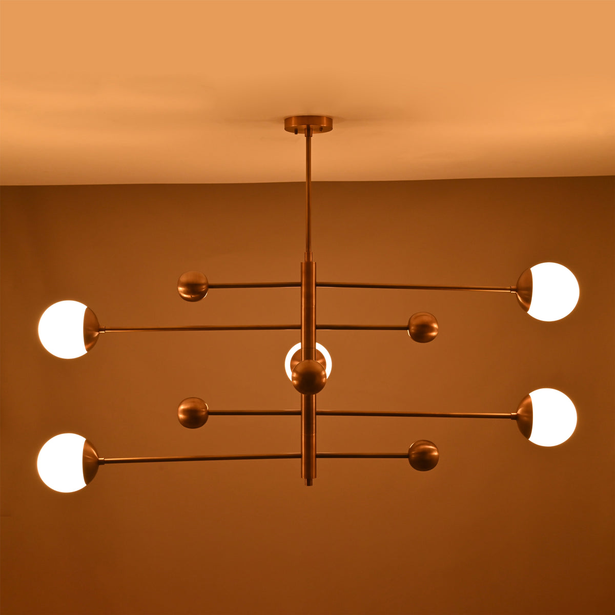 Evening illumination from a 5-light brass chandelier with glowing opal glass globes producing soft, warm ambient light.