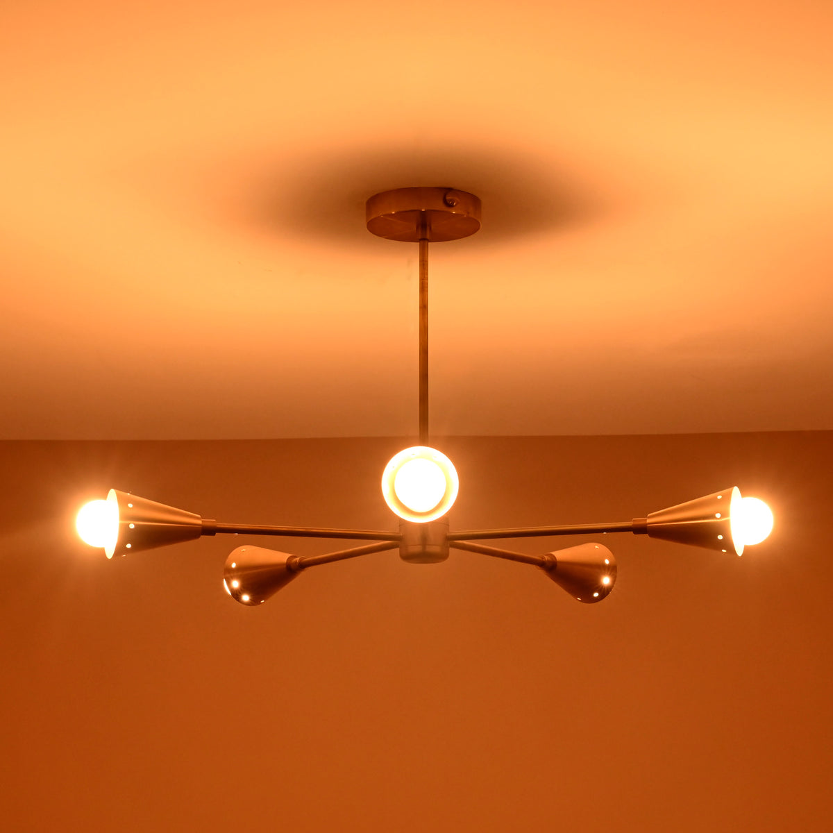 Elegant mid-century brass cone ceiling light glowing warmly against neutral ceiling, handmade by Brass Leaf Studio for timeless modern interiors.