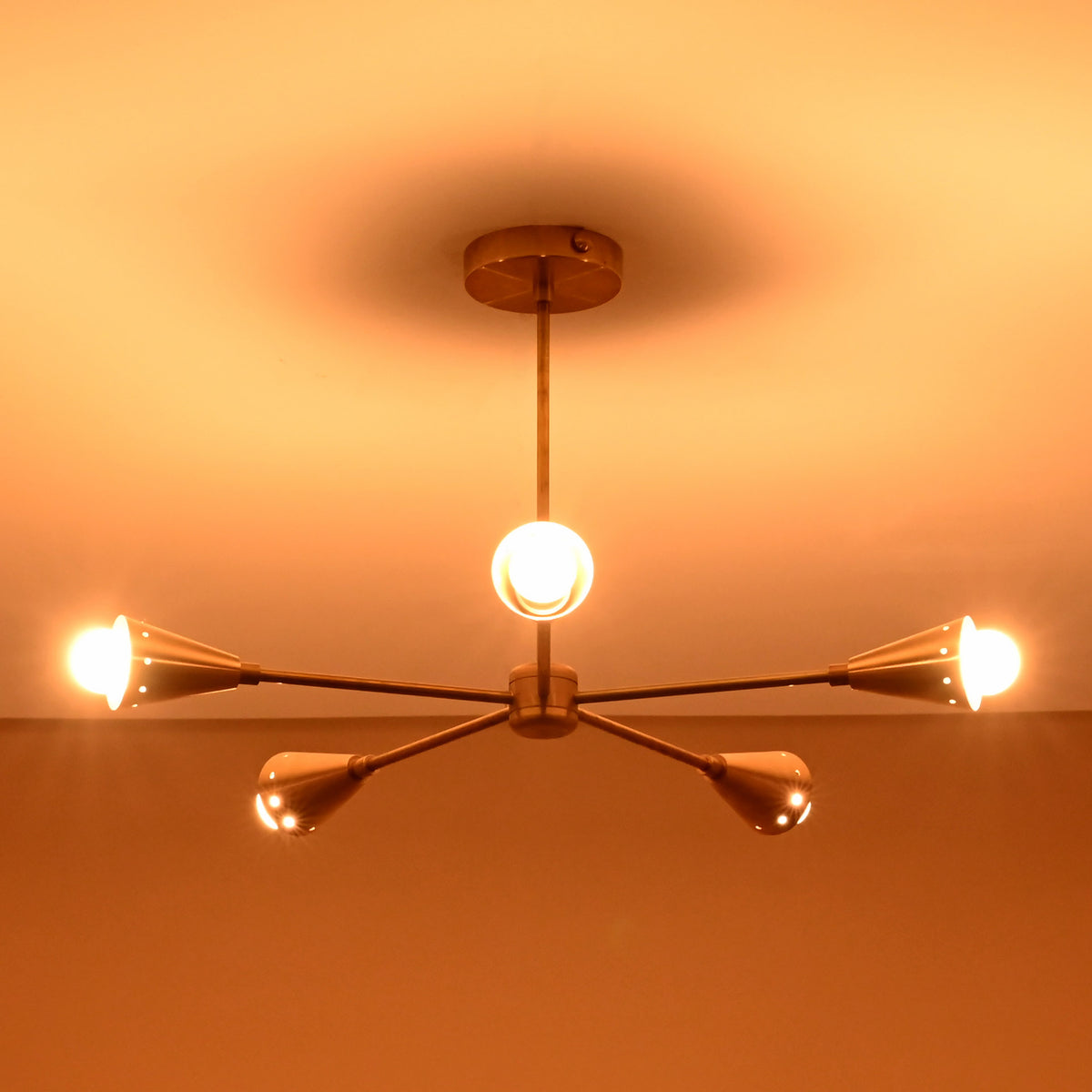 Bottom view of glowing 5-light brass cone chandelier, showing perfect arm balance and polished brass finish craftsmanship.