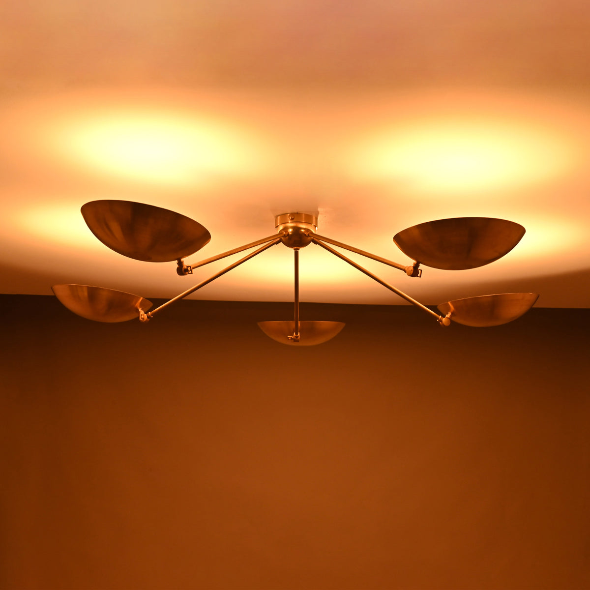 Night view of 5-light brass flushmount chandelier glowing with warm, indirect ceiling illumination.